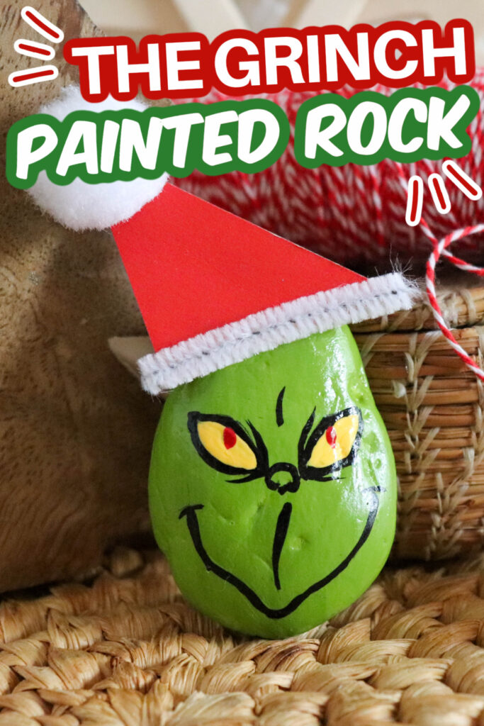 Grinch painted rock sitting on a woven mat