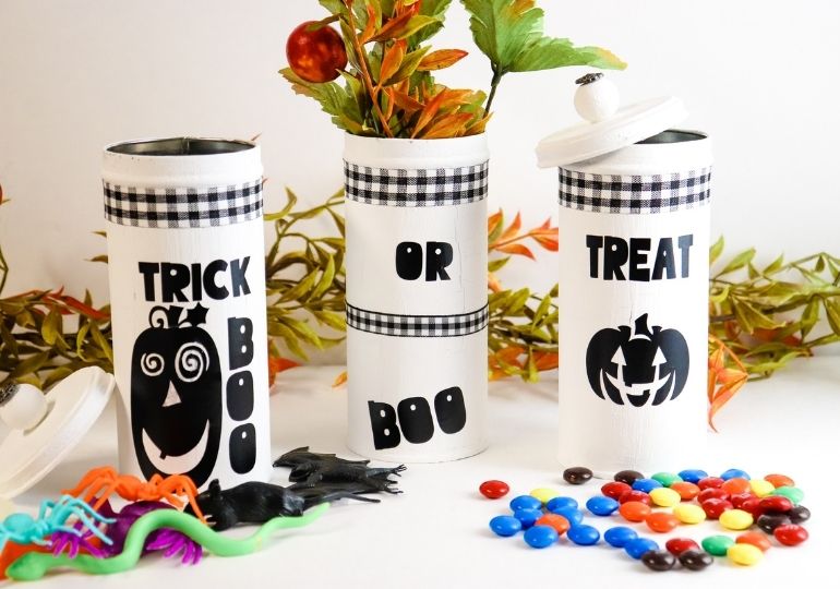 halloween tins on a white table with candy and Halloween toys around it