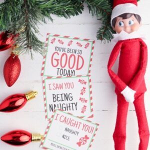 elf on shelf laying on table with printables by it