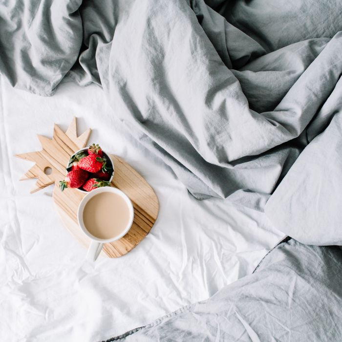 bed with coffee and fruit sitting on the bed 